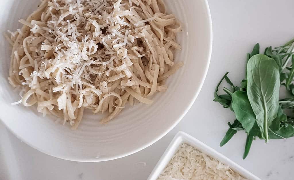 healthy cauliflower alfredo plated with parmesan cheese and fresh arugula