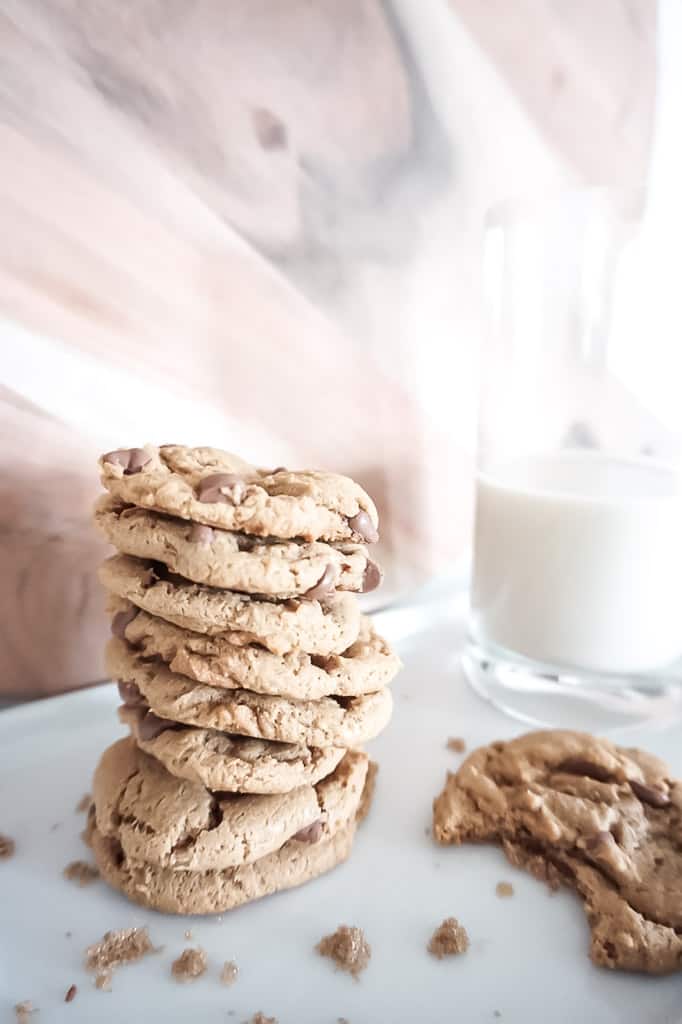 stack of peanut butter chocolate chip cookies, one half eaten cookie, and milk