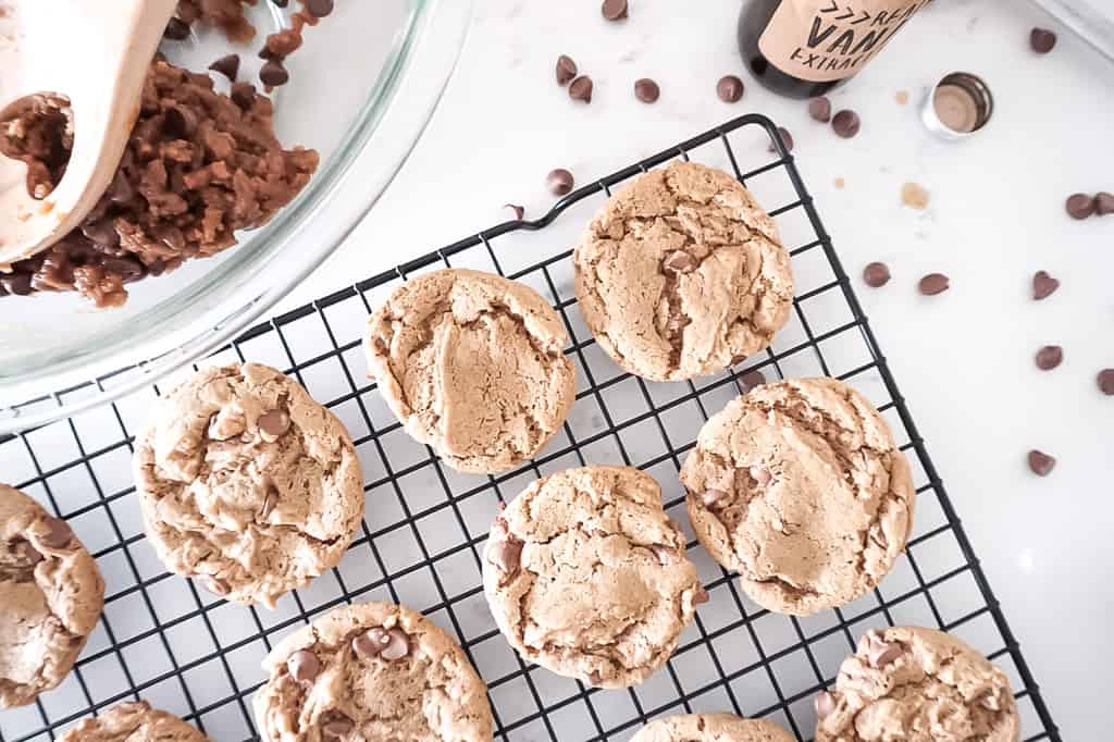 peanut butter chocolate chip cookie cooling on rack with ingredients in the background