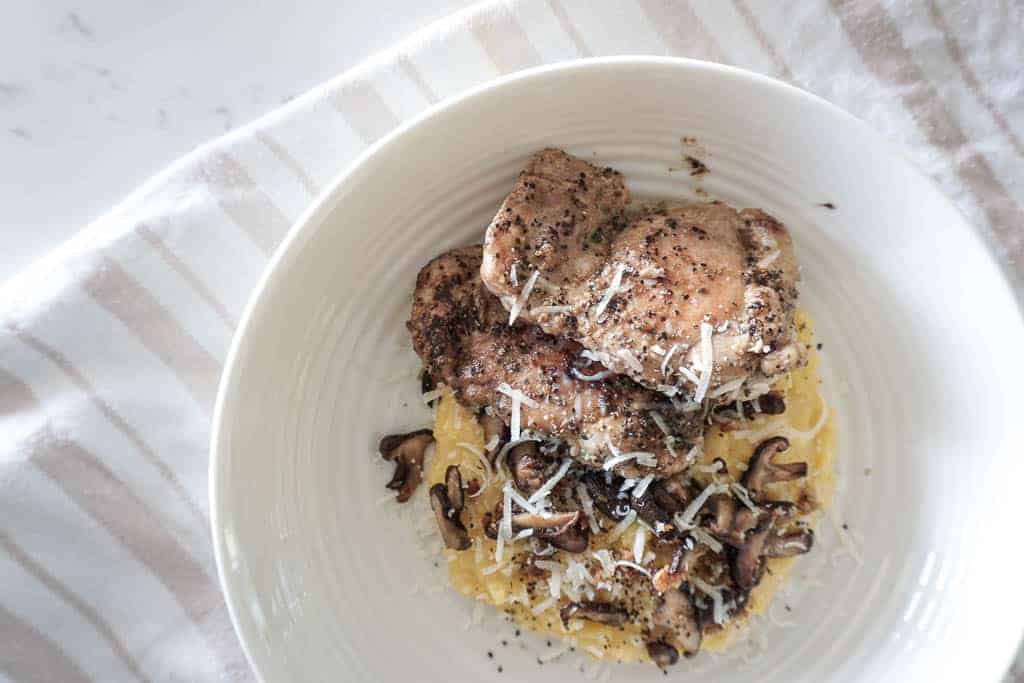 Signed Samantha's chicken and polenta recipe - an overhead shot of polenta in a low pasta bowl with mushrooms, parmesan and topped with chicken