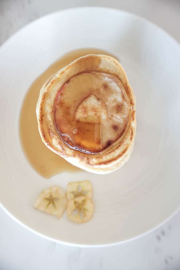 Signed Samantha's apple pancake recipe. A stack of pancakes with round apple slices in the pancakes and syrup on top.