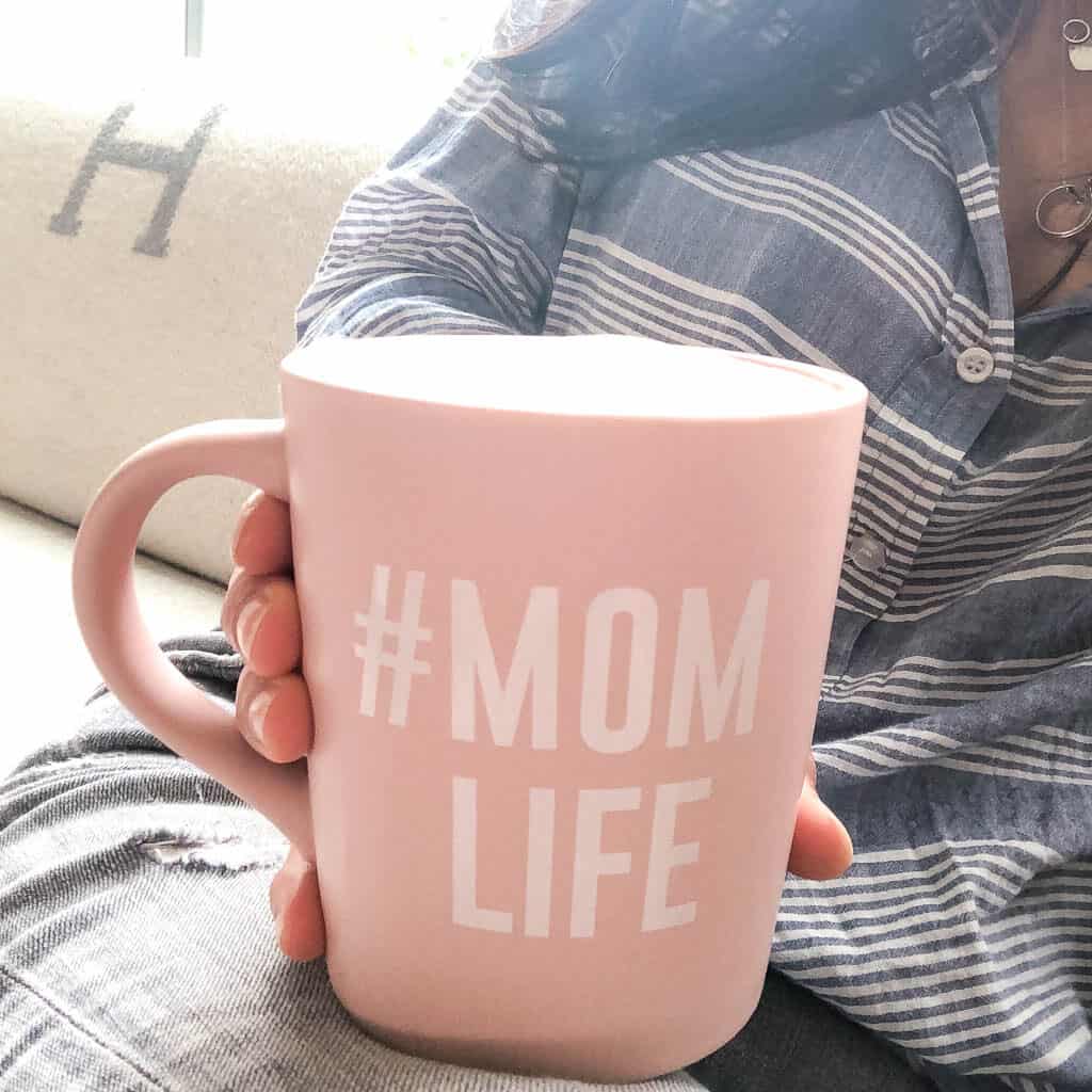 Signed Samantha discussing all of her favorite tea time items. Including an oversized pink mug that says #momlife on it which Samantha is holding in her hands while sitting on the couch. Her legs are on the couch, which the tea mug is resting on and you cannot see her face.