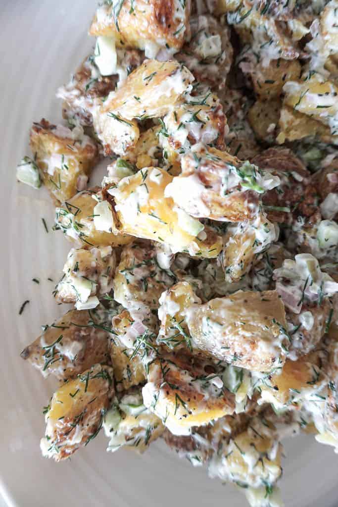 A close up shot of Signed Samantha's vegan potato salad. The potatoes look crispy, there is a ton of creaminess added to them, you can see the dill coming through. vegan potato salad