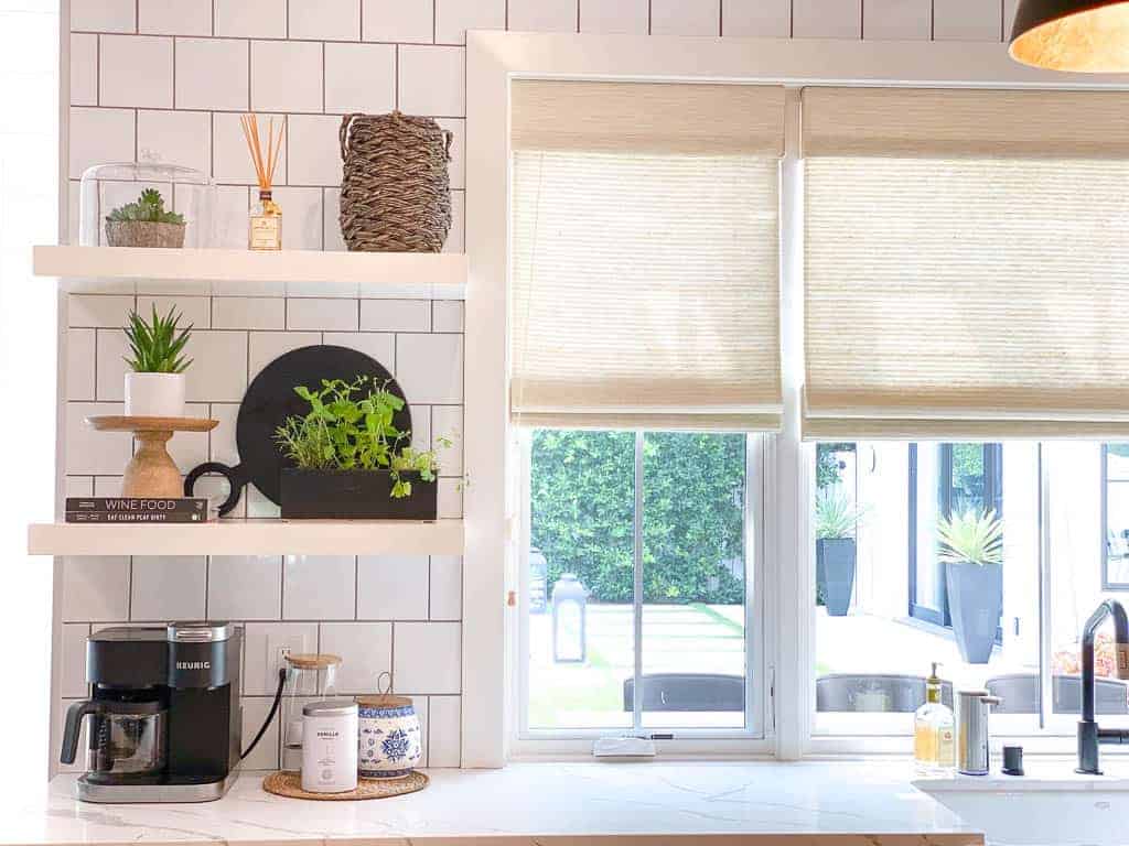 coffee station and floating shelves with decorative items on it are pictured for signed samantha's post on how to style kitchen countertops.