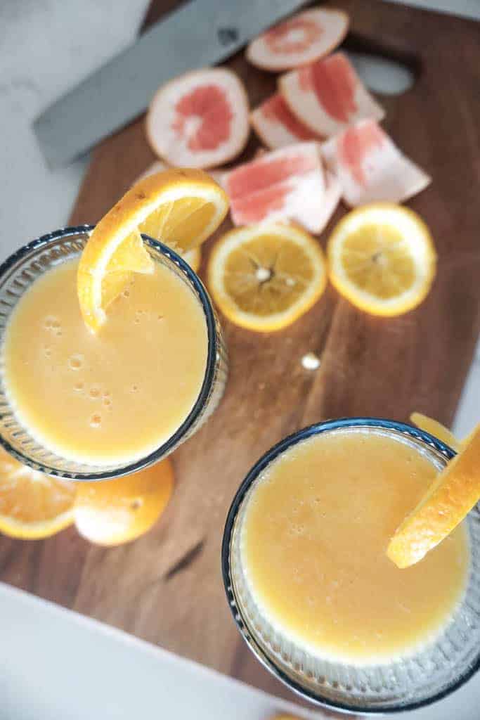 Signed Samantha's recipe for a wine smoothie. Two of the wine smoothies are pictured from overhead. Each has an orange sticking out of the glass. There are grapefruit and orange skins on the cutting board in the background