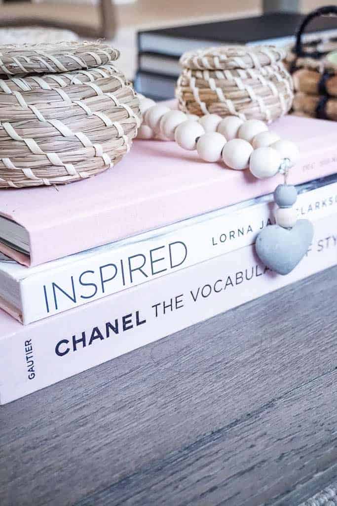 Coffee table style includes coffee table books, three of them all light blush pink, one is Chanel, one is called inspired, and one is a family photo album