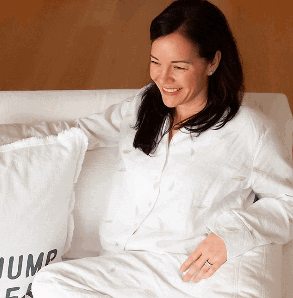 October Local Love Includes Jammy and CO PJs pictured here on a woman who is sitting on the couch. The PJS are white linen.