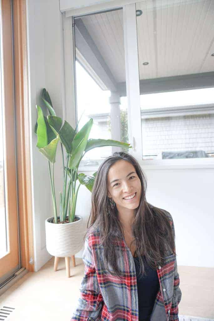 Signed Samantha's winter wardrobe staples includes a plaid shirt - as she is wearing in this image with a plant in the background.