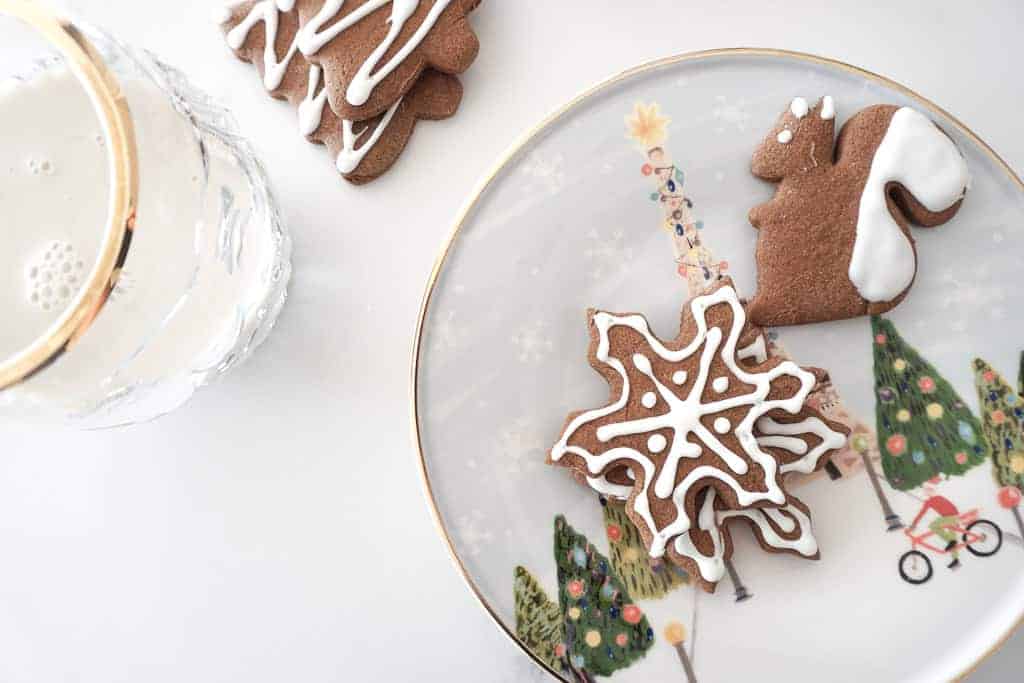 Gluten free gingerbread cookies are pictured on a plate. There is a squirrel, snowflake, and trees. The trees are sitting on the counter