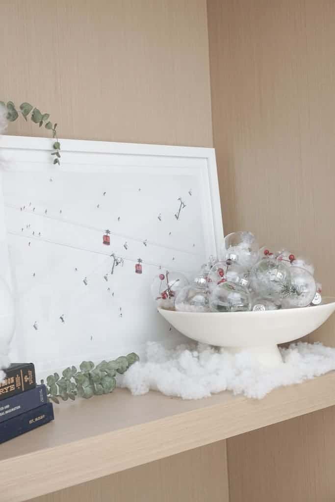 How to Make your home feel more festive includes using ornaments in other places than the christmas tree as pictured in a bowl on a shelf.