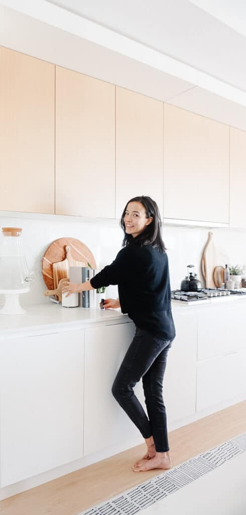 Signed Samantha standing in her kitchen putting some oils into her diffuser to create a signature scent for her home. One of the ways she suggests you can make your home feel like a hotel.