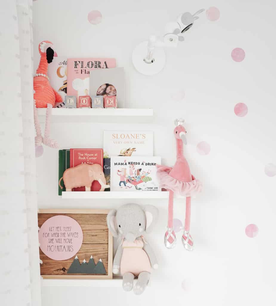 Sloane's nursery tour includes decorative shelving with books, blocks, stuffed animals, and a piece of wood art on it