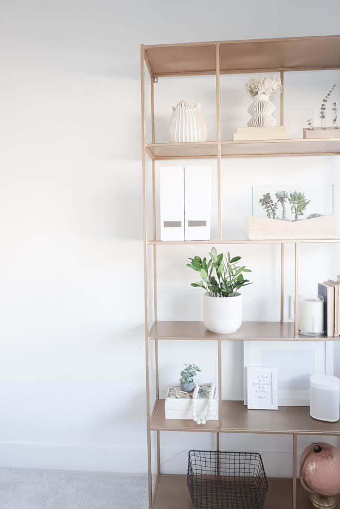 Sharing how to style shelves - showing the completed version on a gold shelf that has books, plants, vases, prayer beads, and file holders.