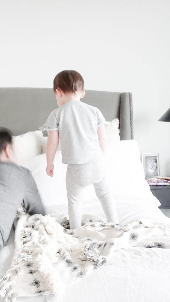 Splurge vs. save home decor edition with Signed Samantha - her daugther Sloane and husband McGregor playing on the bed. The purpose is to illustrate the bedframe, which is a splurge item for Samantha.