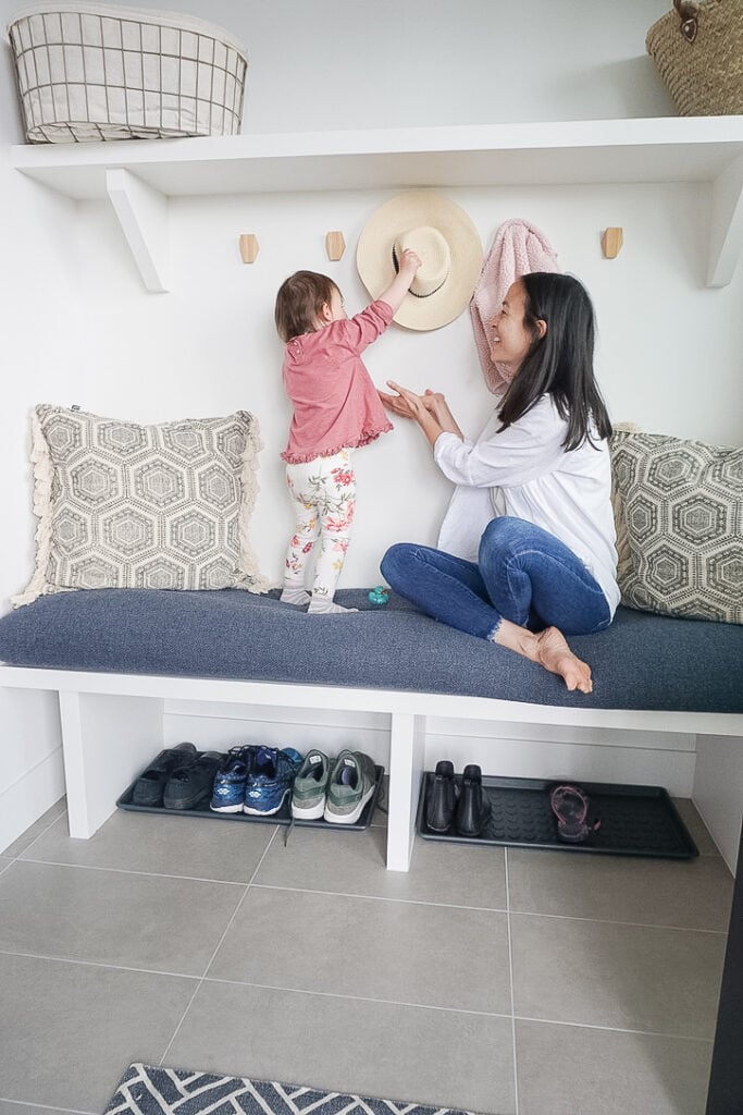 Samantha Potter and her toddler daughter Sloane sitting on a freshly made DIY bench cushion cover that is a blue, almost denim type material