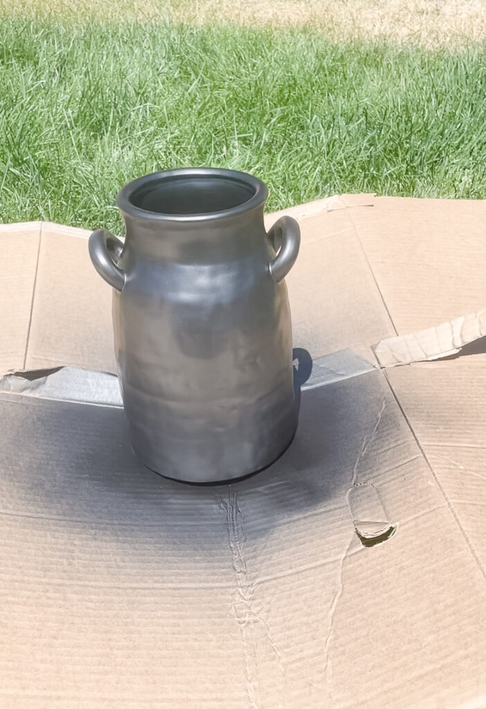 The process of making your own antique vase - step one includes painting it black - which is what is picutred, a vase recently spray painted back on top of cardboard.