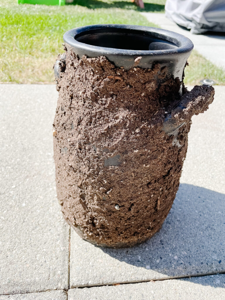 DIY antique vase making in the process - there is a vase recently painted black with a bunch of mud on it drying.