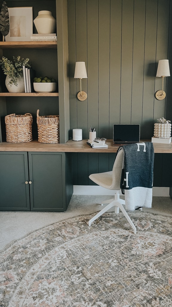 green home office with cabinets on the ground, a bookshelf above and a desktop in between. the green is a rich mossy green that compliments the cream of the office chair.