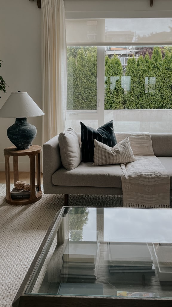 sofa with a blanket nicely styled across the back of the sofa. the blanket is folded with several pillows.