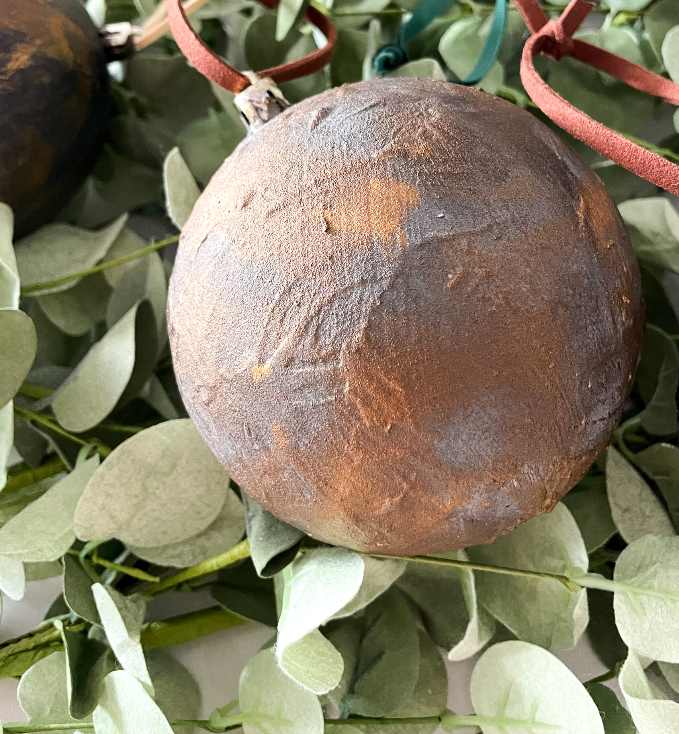 DIY Antiqued Christmas Ornaments on top of eucalyptus