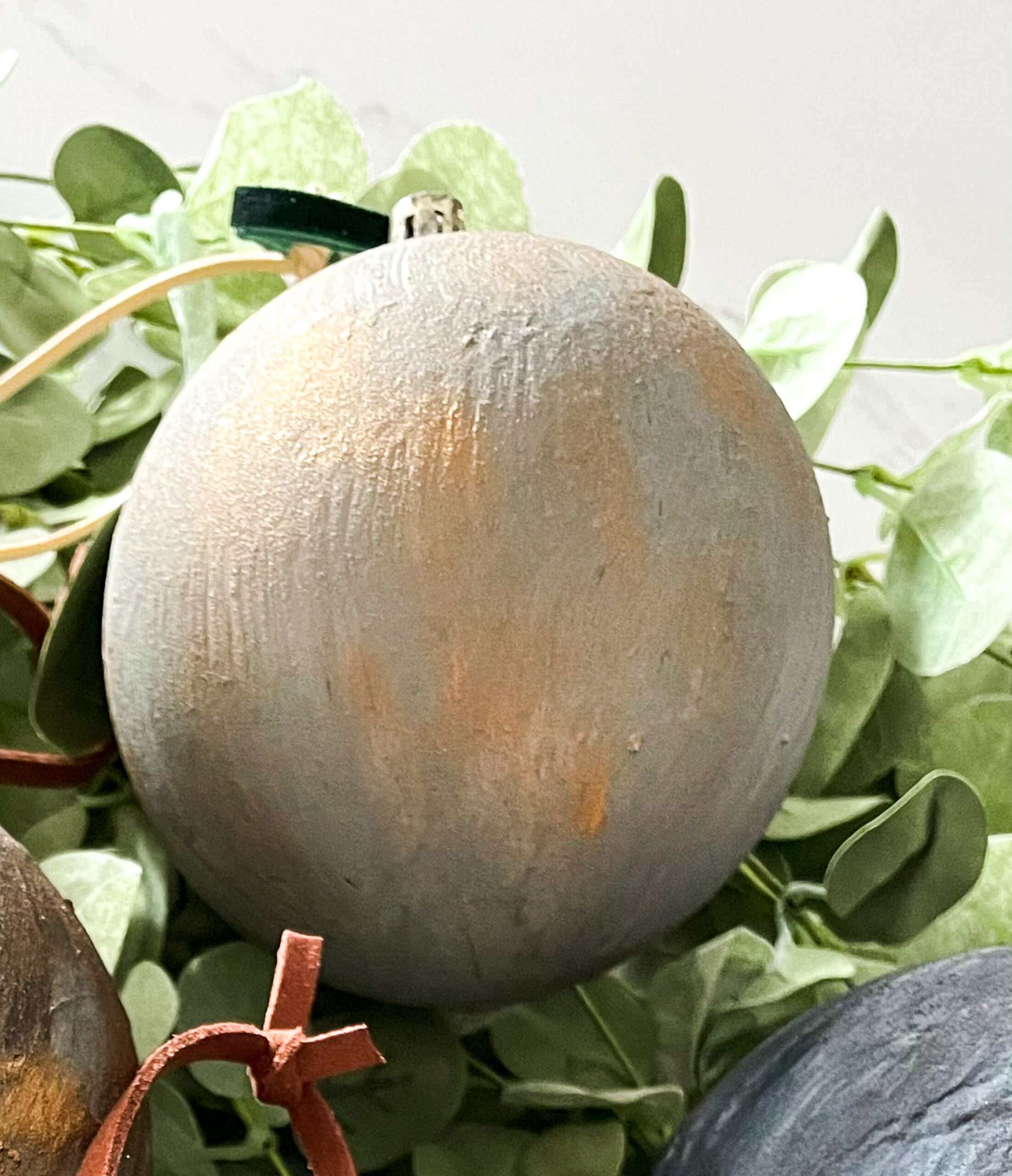 DIY Antiqued Christmas Ornaments on top of eucalyptus