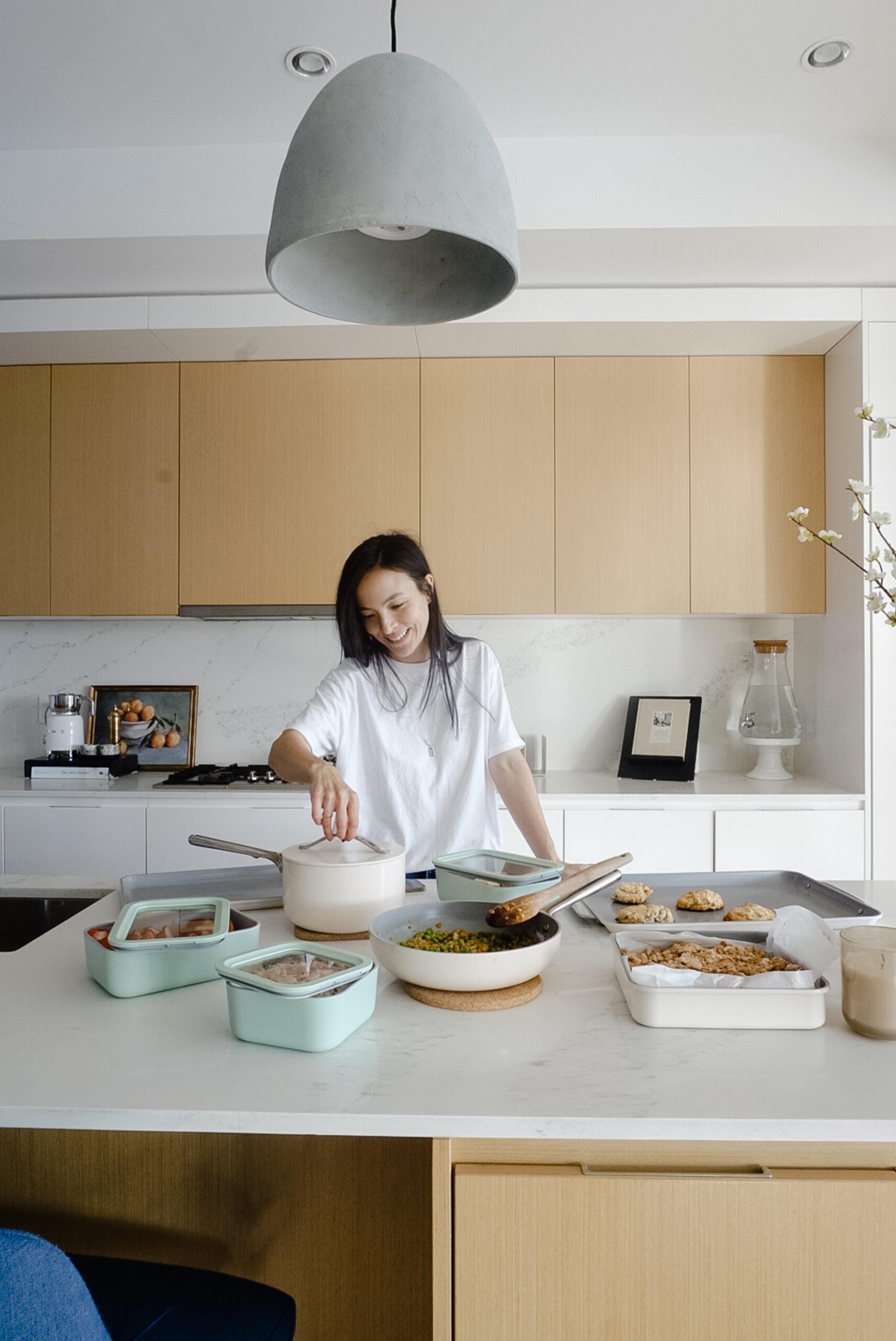 Signed samantha standing in front of her complete caraway kitchen pictured - a tea kettle, baking trays and dishes, and pots and pans