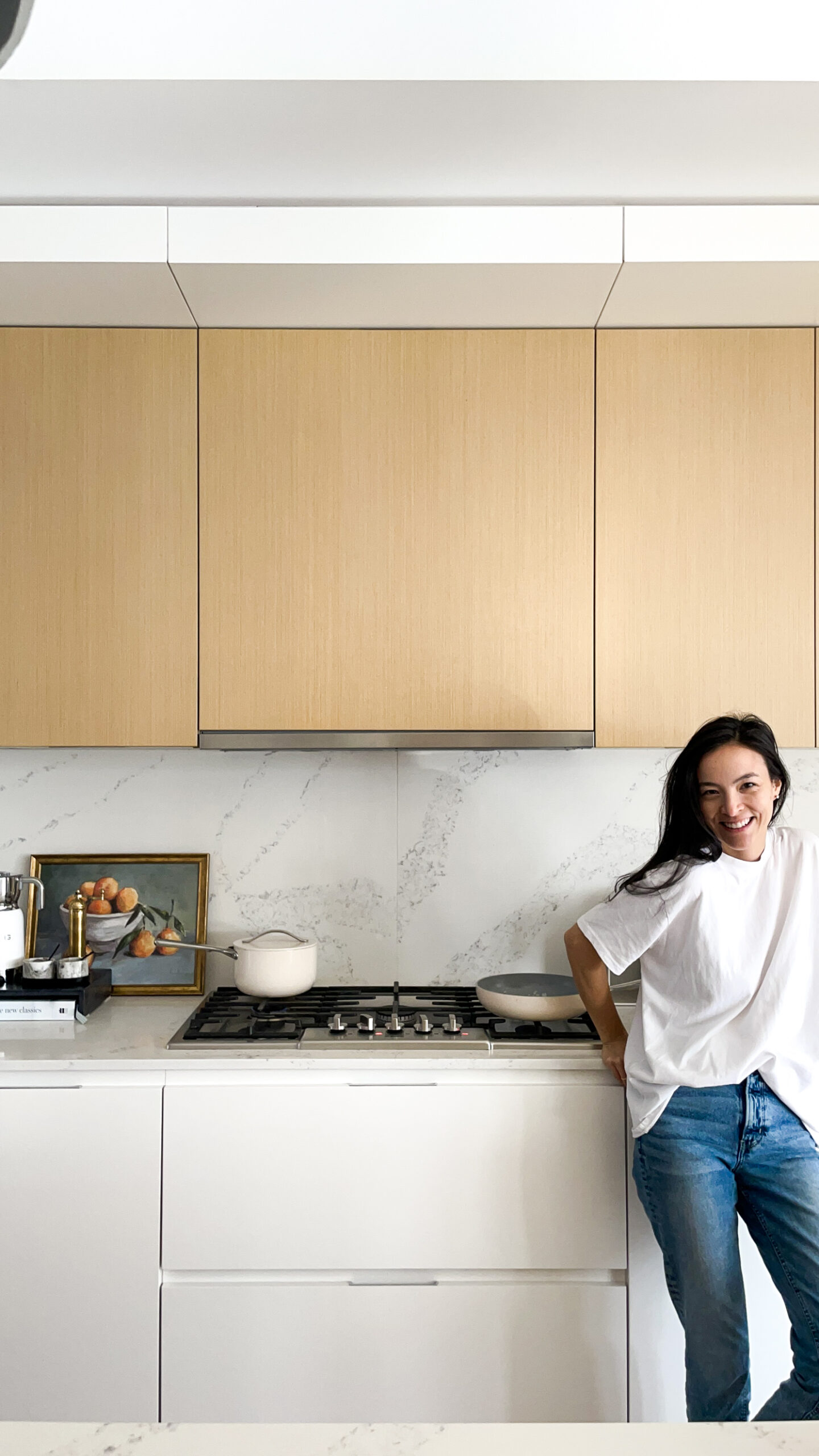 Signed samantha standing in front of her complete caraway kitchen pictured - a tea kettle, baking trays and dishes, and pots and pans