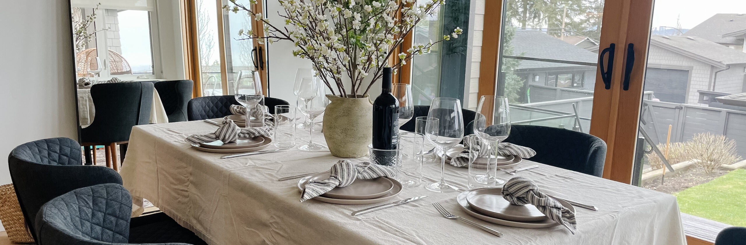 dining room with a set table, wine glasses, dishes, spring flowers