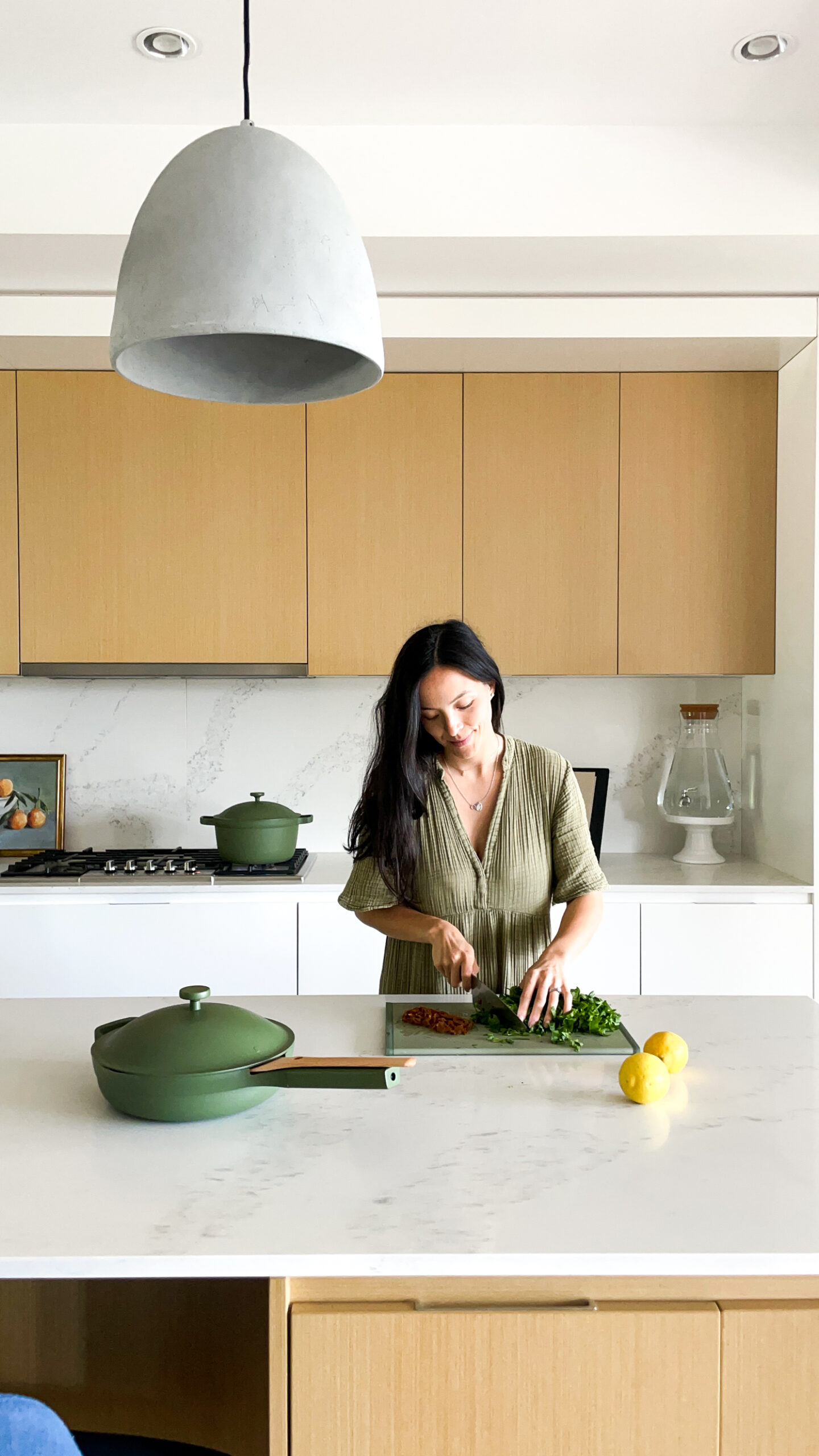 Samantha cooking in the kitchen, chopping items on her our place cutting board with the always pan 2.0 in the foreground