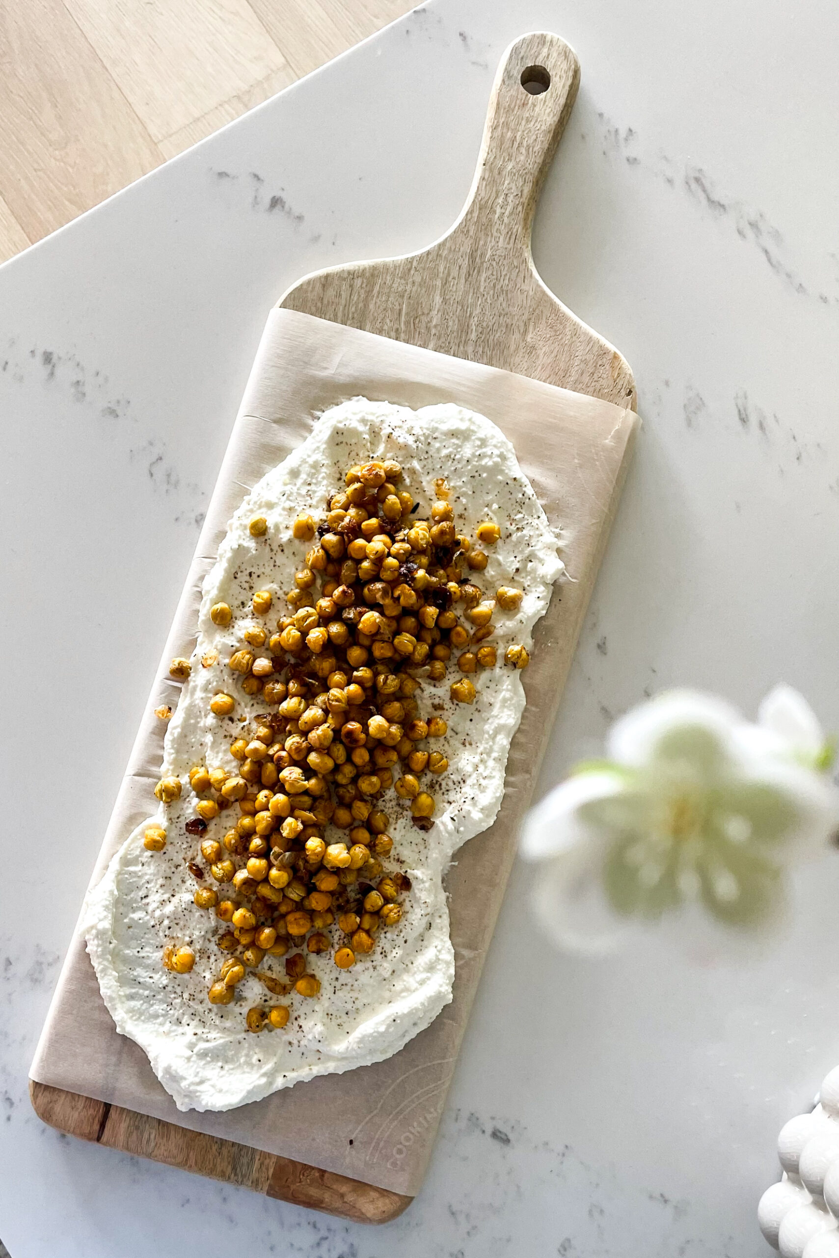 A delicious and simple honey whipped feta on a board with roasted chickpeas overtop