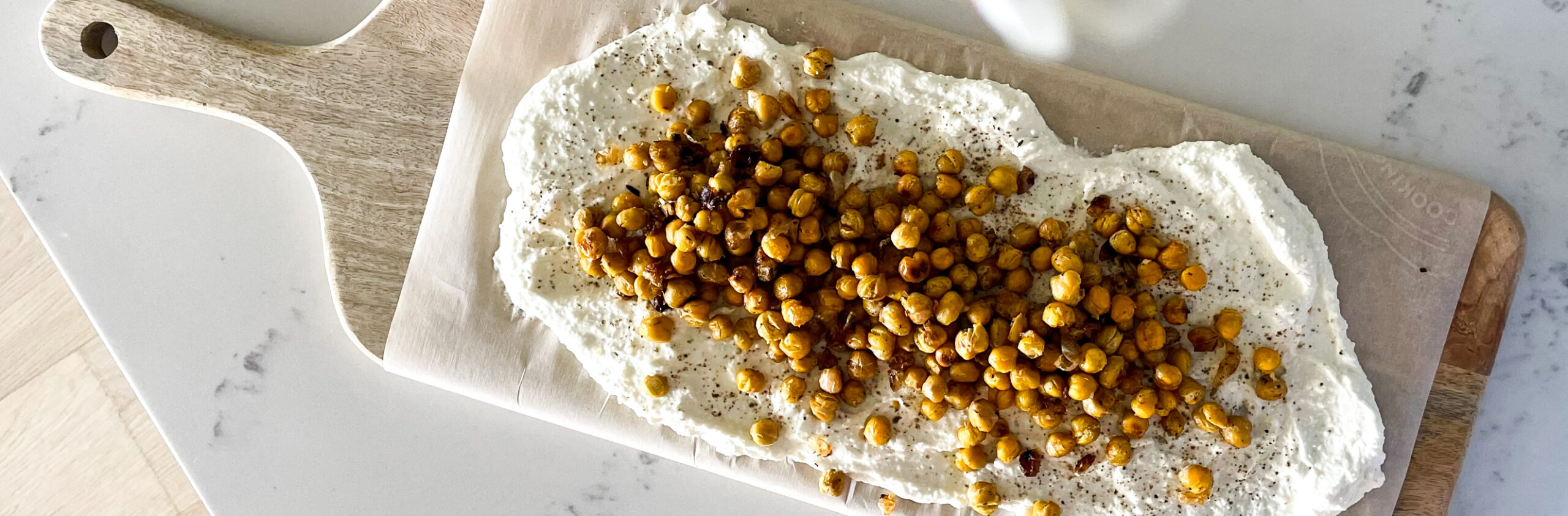 A delicious and simple honey whipped feta on a board with roasted chickpeas overtop