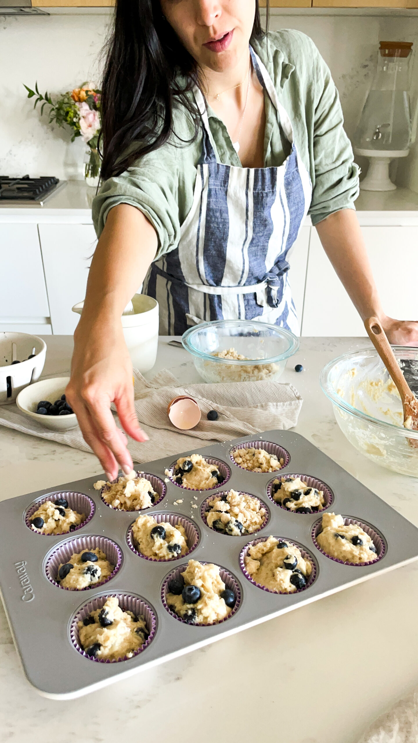 signed samantha making gluten-free blueberry lemon muffins and adding the crumb topping