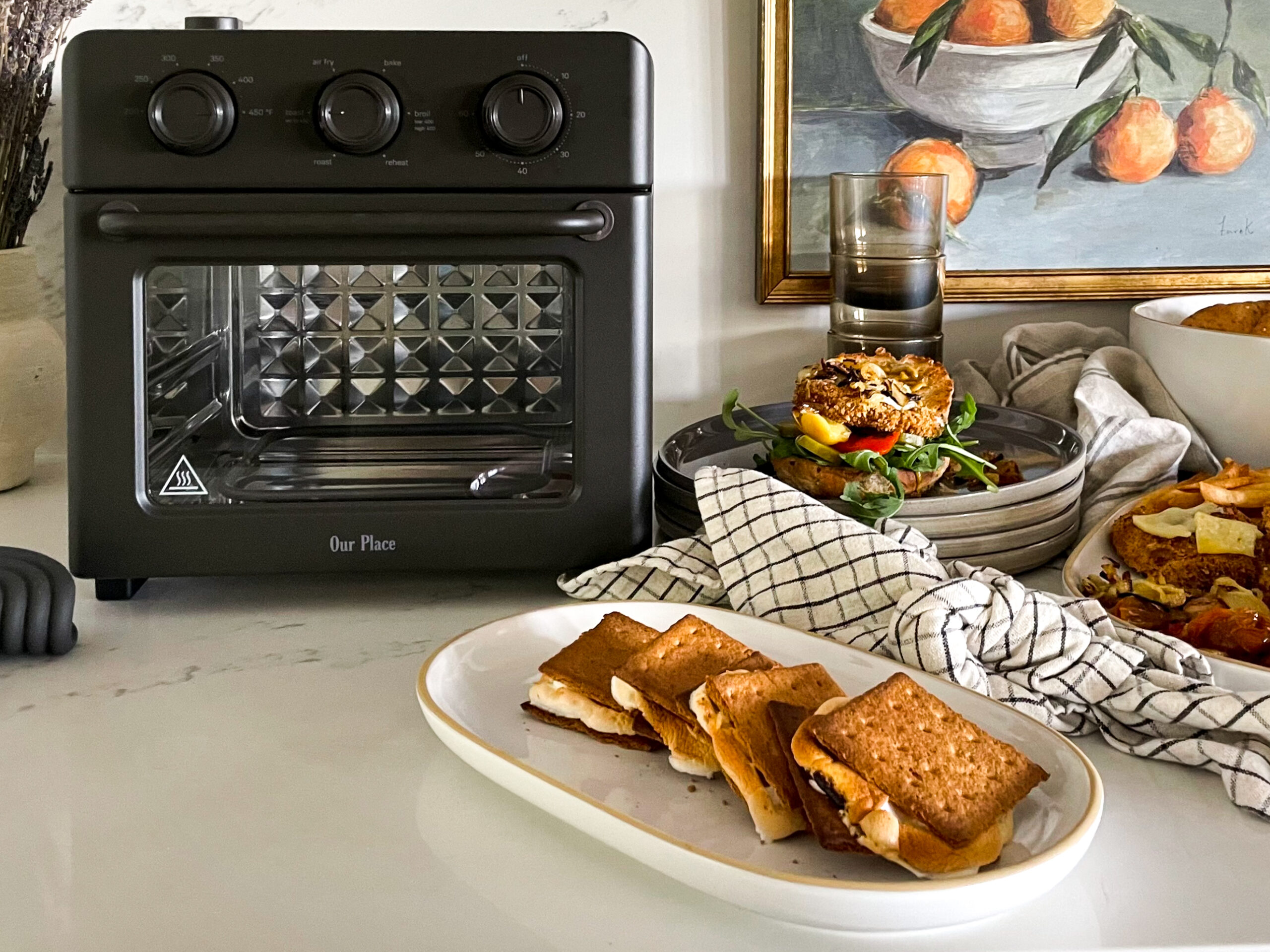 Our place wonder oven on the counter surrounded by delicious food all made in the oven