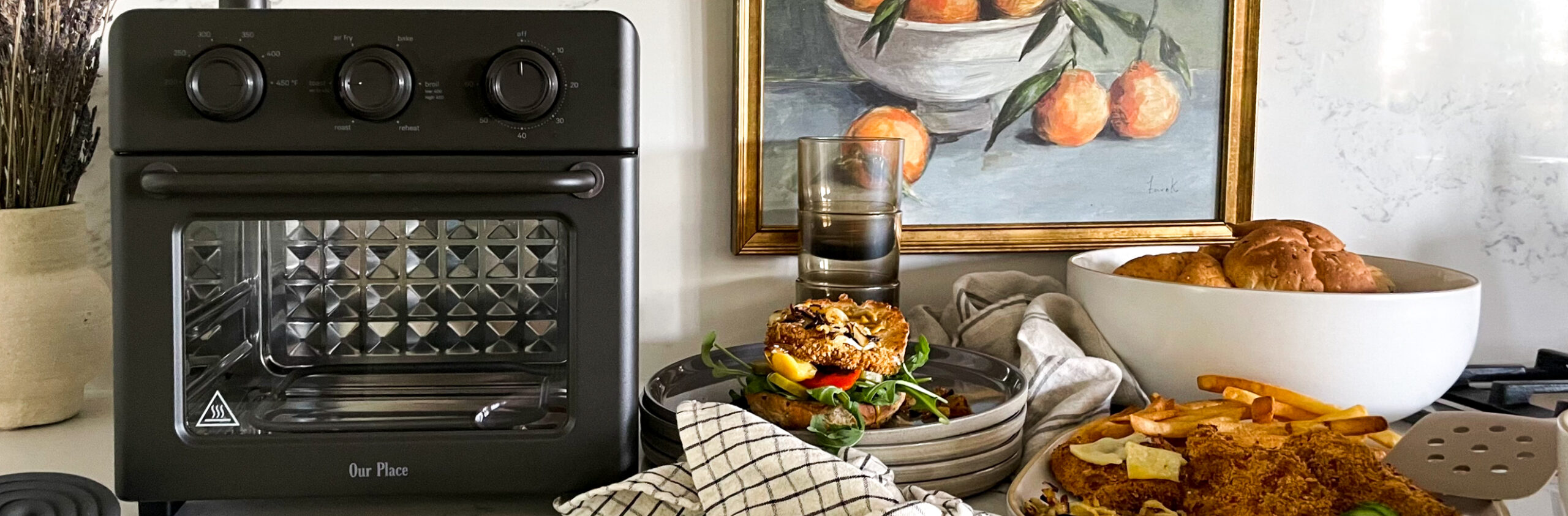 Our place wonder oven on the counter surrounded by delicious food all made in the oven