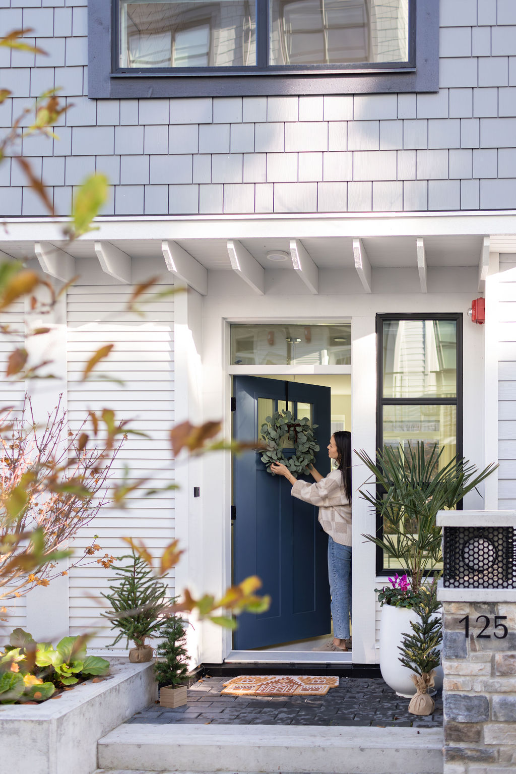 Woman putting wreath on door on a townhome - Eastwoods by Anthem in Maplewood North Vancouver