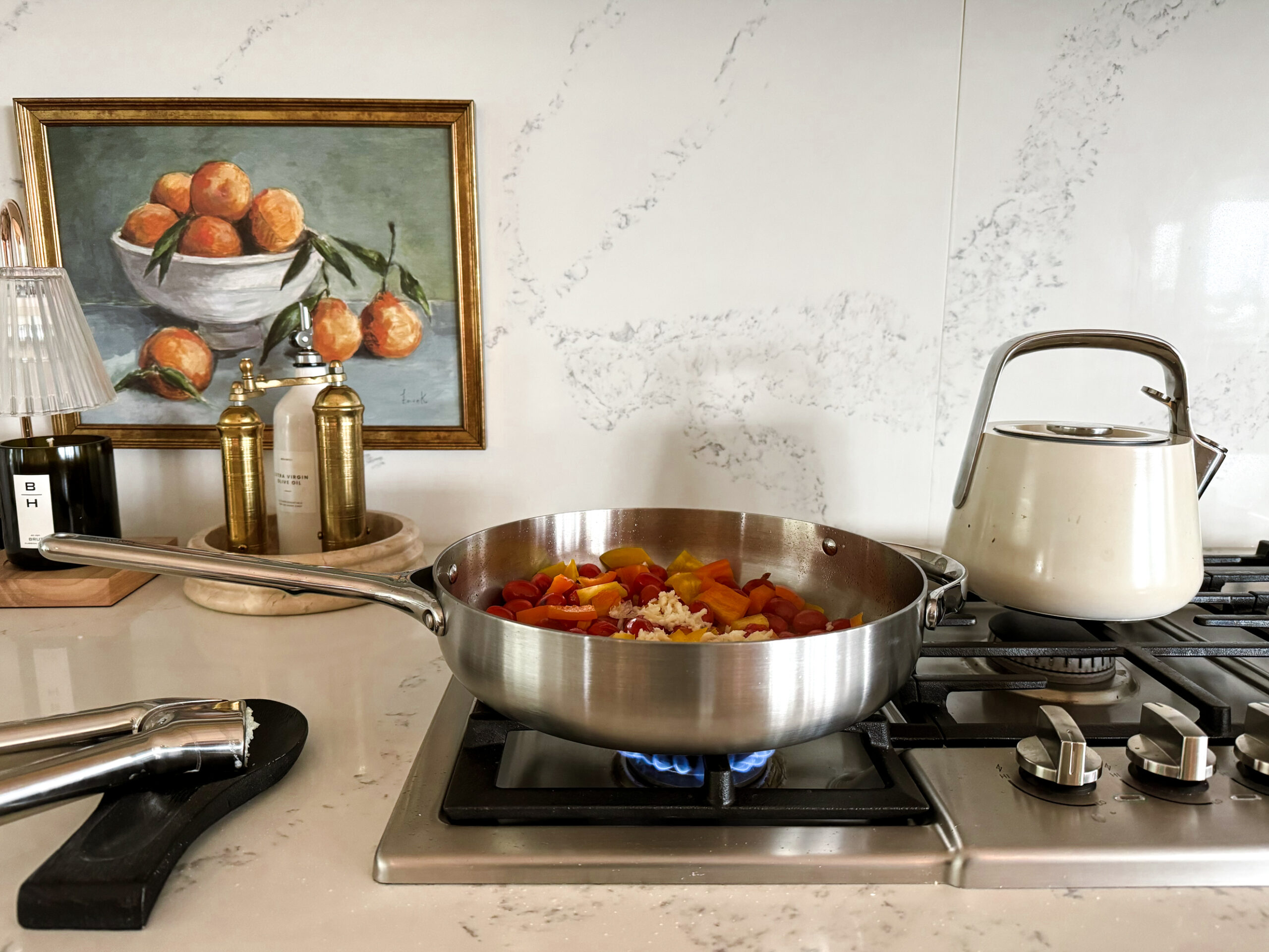 Cooking tomatoes and peppers on the stove top using Caraway's new stainless steel pans as part of a review of the products.