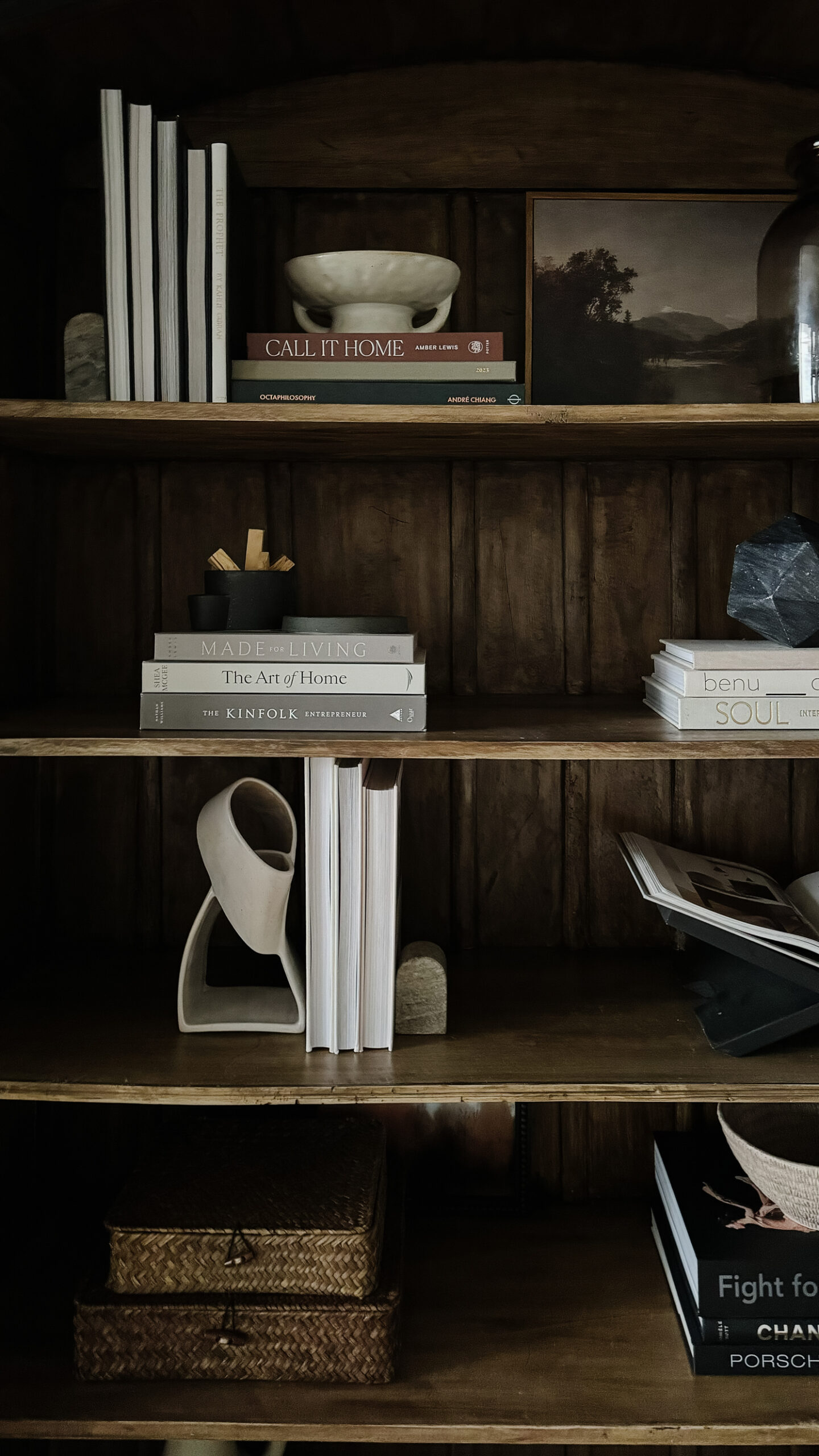 Styling Shelves - a black bookshelf cabinet that is arched with wood interior having been styled with vases, pots, books, etc. is on display