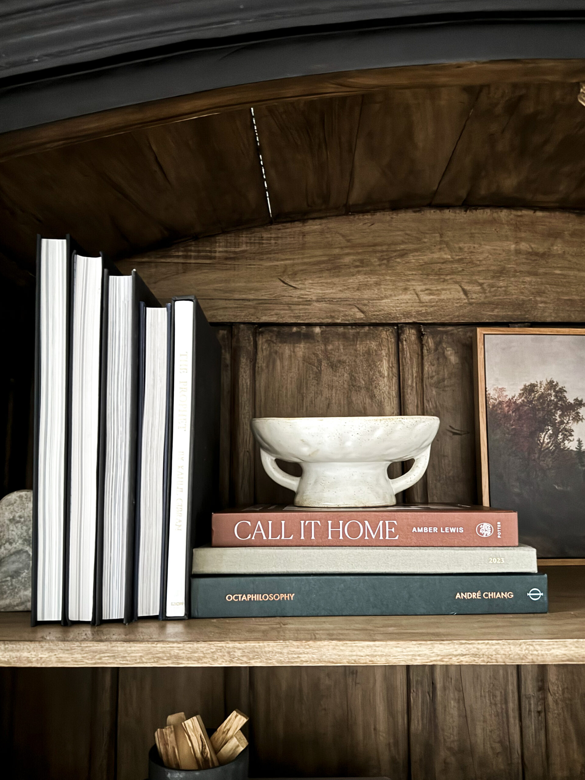 Styling Shelves - a black bookshelf cabinet that is arched with wood interior having been styled with vases, pots, books, etc. is on display