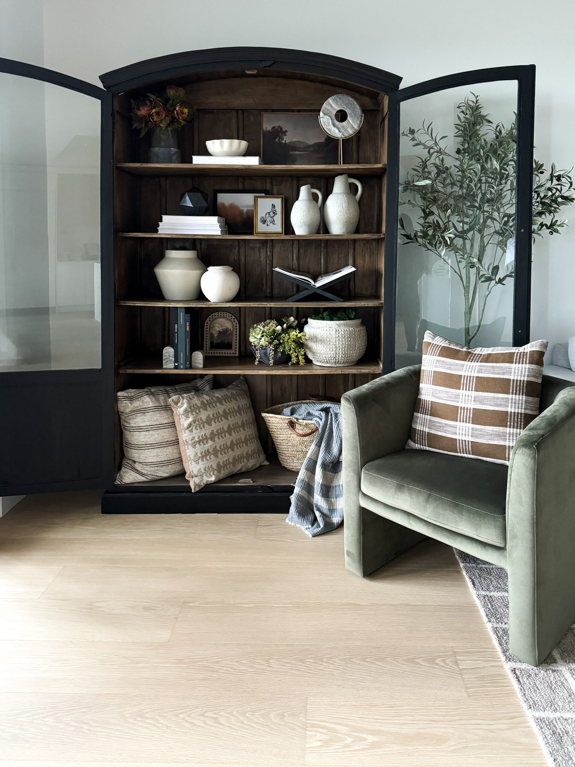 Styling Shelves - a black bookshelf cabinet that is arched with wood interior having been styled with vases, pots, books, etc. is on display